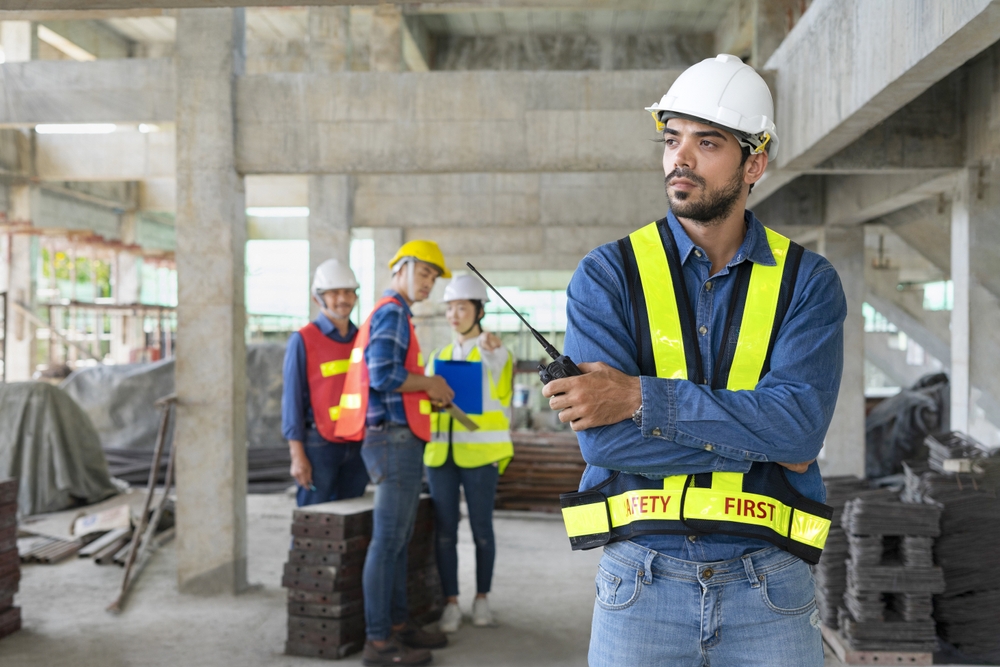 Young,Confident,Engineer,With,Arms,Crossed,holding,Walkie,Talkie,,Standing,Under
