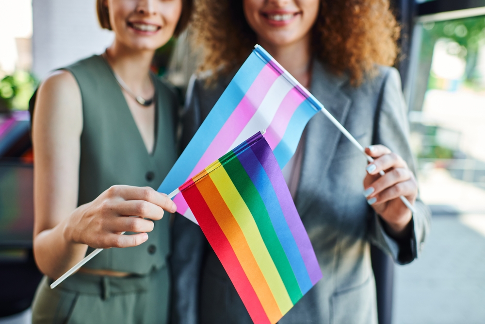 Two,Coworkers,Joyfully,Display,Pride,Flags,,Symbolizing,Inclusivity,And,Support